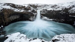 a large waterfall is surrounded by snow covered rocks