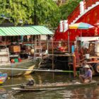 A man rows a boat in a bustling floating market
