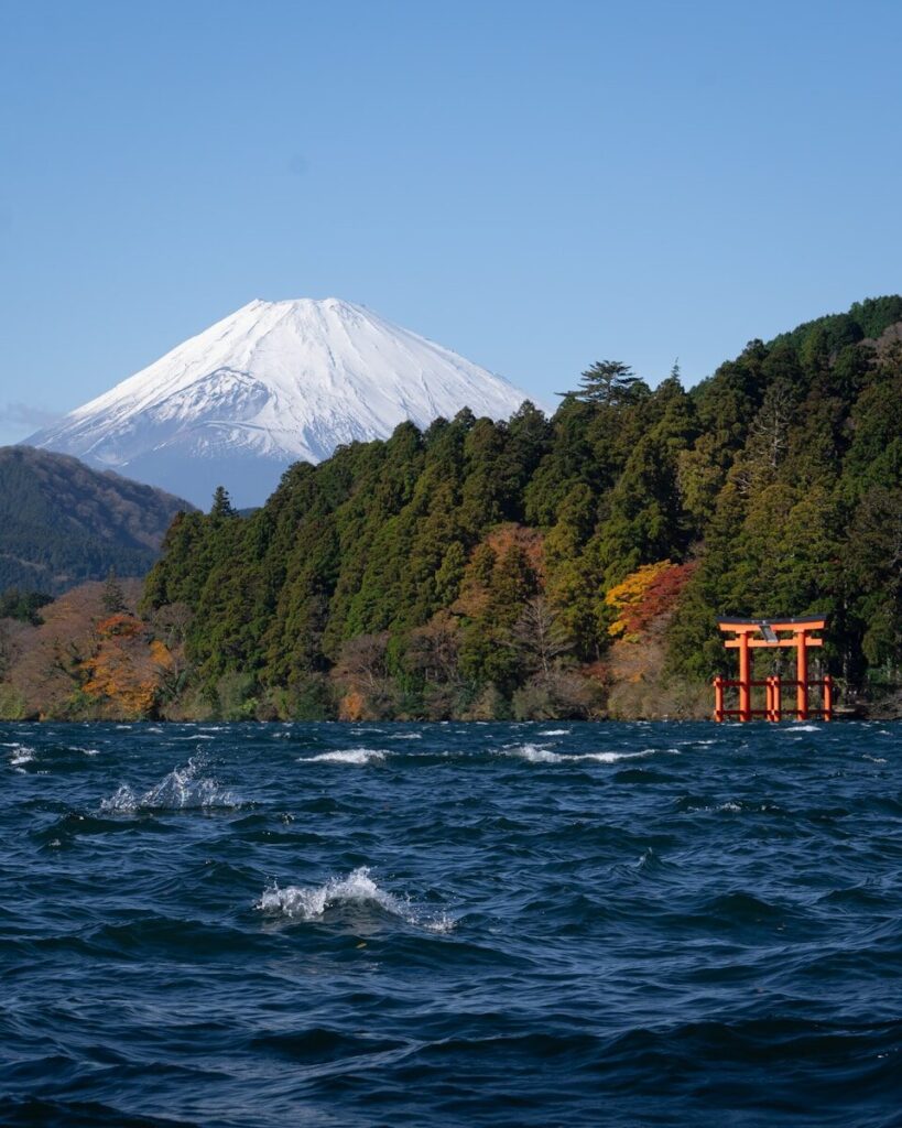 Mount Fuji seen across Lake Ashi in Hakone, with a red torii gate at the shoreline