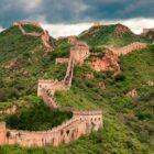 The Great Wall of China winding over green mountain ridges under a cloudy sky