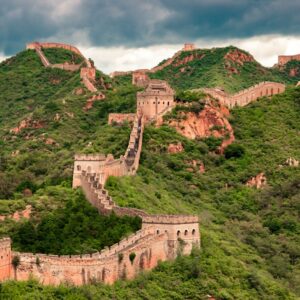 The Great Wall of China winding over green mountain ridges under a cloudy sky