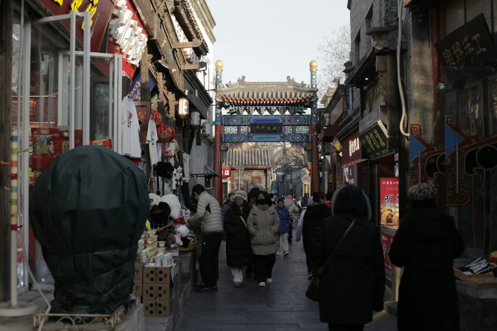 People walk down a narrow street lined with shops