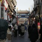 People walk down a narrow street lined with shops