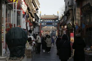 People walk down a narrow street lined with shops